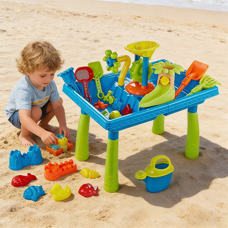 A little boy plays with toys beside the sand table on the sunny beach