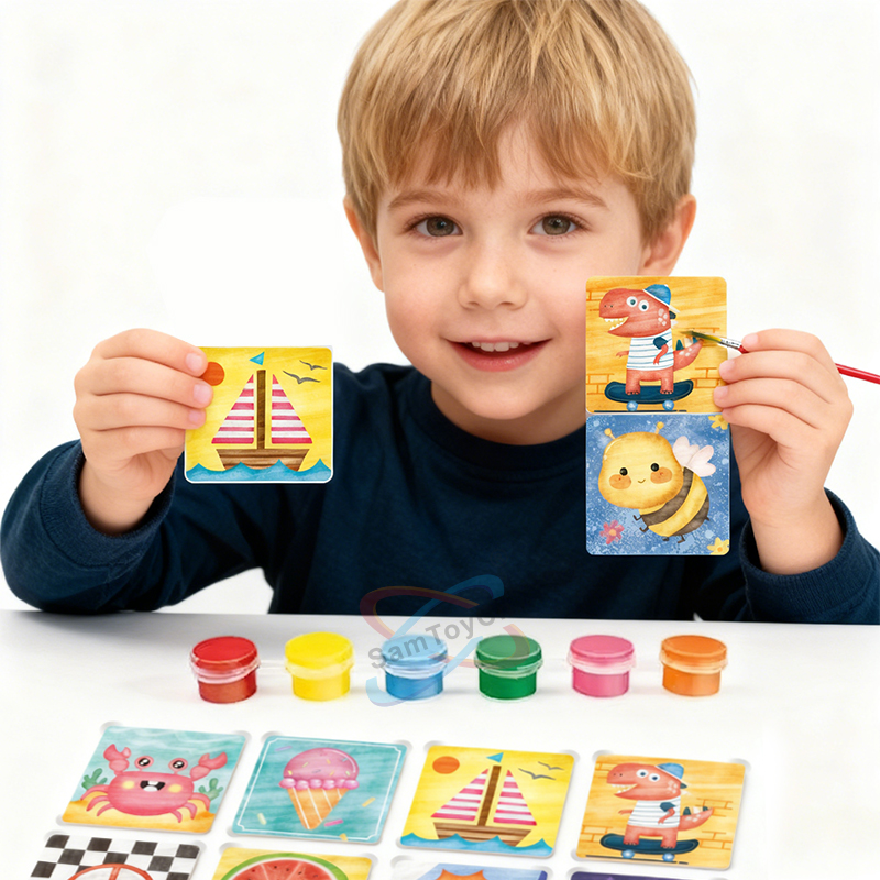 A little boy in a dark blue outfit holds a paintbrush and a Tile Art Fridge Magnet. On the table lie colorful paints and refrigerator magnets
